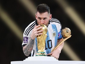 DECEMBER 18: Lionel Messi of Argentina kisses the FIFA World Cup Winners' Trophy while holding the adidas Golden Boot award after the FIFA World Cup Qatar 2022 Final match between Argentina and France at Lusail Stadium on December 18, 2022 in Lusail City, Qatar.