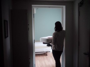 A staff member carries bedding in one of the suites at Toronto's Interval House, an emergency shelter for women in abusive situations, on Feb. 6, 2017. A new report shows emergency shelters in Alberta haven't been able to provide refuge to thousands of women who are fleeing domestic violence due to a lack of space.