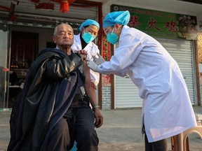A resident (L) receives a Covid-19 vaccine in Danzhai county, Qiandongnan Miao and Dong Autonomous Prefecture, in China's southwestern Guizhou province on December 12, 2022, as medical workers vaccinate people who can't go out conveniently from their homes.
