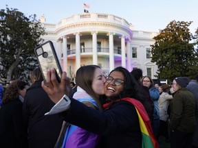 Aparna Shrivastava, right, takes a photo as Shelby Teeter gives her a kiss, after President Joe Biden signed the Respect for Marriage Act, Tuesday, Dec. 13, 2022, on the South Lawn of the White House in Washington.