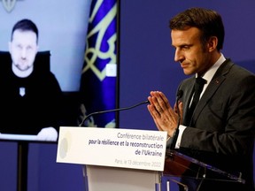 Ukrainian President Volodymyr Zelensky (L) is displayed on a TV screen next to French President Emmanuel Macron delivering a speech during the French-Ukrainian conference for resilience and reconstruction at the Ministry of Economy in Paris on December 13, 2022.