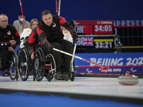 Canada's Mark Ideson pushes a stone as he and his teammates play against Norway during their wheelchair curling competition at the 2022 Winter Paralympics, Thursday, March 10, 2022, in Beijing.
