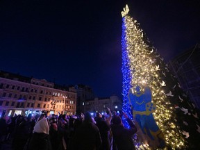 People take selfie photographs during the unveiling ceremony of Kyiv's main Christmas tree  on St. Sophia Square in the Ukrainian capital of Kyiv, on December 19, 2022. (Photo by Sergei SUPINSKY / AFP)