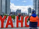 People interact with a YAHOO sign that was installed in Calgary's East Village area ahead of the 2022 Stampede, June 24, 2022.