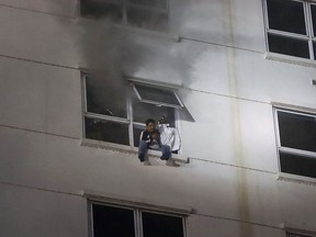 A man sits on a window ledge as a fire burns through the Grand Diamond City hotel-casino in Poipet on December 29, 2022.