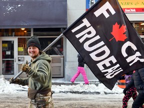 A protester carries a flag showing his displeasure with the COVID mandates imposed by Prime Minister Justin Trudeau, during the Freedom Convoy protest in Ottawa, February 5, 2022.