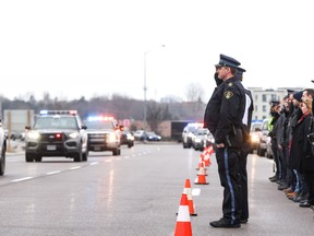 Members of the Ontario Provincial Police Orillia Detachment pay their respects as the hearse carrying Const. Grzegorz "Greg" Pierzchala arrives  in Barrie, Ontario from Highway 400 on Friday December 30, 2022. THE CANADIAN PRESS/Christopher Drost
