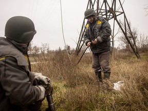 Electricity workers brought in from Odessa, wearing bulletproof vests and helmets, work to fix a destroyed power line on December 1, 2022 in Kherson, Ukraine.