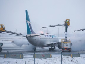 A WestJet Boeing 737 is de-iced at the Calgary International Airport on December 20, 2022.