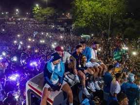 Argentina captain and forward Lionel Messi holds the FIFA World Cup trophy as he and teammates ride on top of a bus during a celebration in Ezeiza, Buenos Aires province, Argentina, on Dec. 20, 2022.