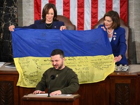 Ukrainian President Volodymyr Zelenskyy addresses the US Congress while US Vice President Kamala Harris, left, and House Speaker Nancy Pelosi hold a flag given to them by Ukrainian President Volodymyr Zelenskyy when he left December 21 speaking before Congress in 2022. Almond Ngan / AFP