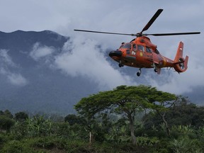 Members of the National Search and Rescue Agency (BASARNAS) flies a helicopter to deliver relief goods to a village affected by Monday's earthquake in Cianjur, West Java, Indonesia, Saturday, Nov. 26, 2022. The magnitude 5.6 quake killed hundreds of people, many of them children, and displaced tens of thousands.