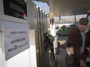 A driver fills up his car while sign on pump reads 'Dear Costumers! You can purchase only 2 liters of fuel at the regulated price!' in Martonvasar Hungary, Thursday, Dec. 1, 2022. Drivers in Hungary are running into fuel shortages at filling stations as a government-imposed price cap on fuel squeezes independent stations and leaves the state energy company struggling to keep up with demand.