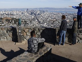 Tourists look out onto the city skyline from Christmas Tree Point on top of Twin Peaks in San Francisco, Thursday, Dec. 15, 2022.