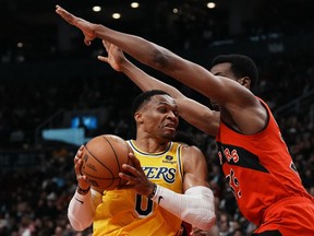 Los Angeles Lakers' Russell Westbrook (left) is guarded by Toronto Raptors' Christian Koloko as he drives to the basket during first half NBA basketball action in Toronto on Wednesday, December 7, 2022.