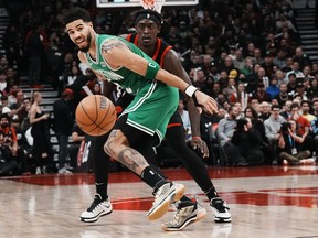 Boston Celtics Jayson Tatum, left, and Toronto Raptors Pascal Siakam eye a loose ball during first half NBA basketball action in Toronto, Monday, Dec. 5, 2022.&ampnbsp;Tatum had 31 points and 12 rebounds to lift the league-leading Boston Celtics to a 115-110 victory over the Toronto Raptors on Monday.