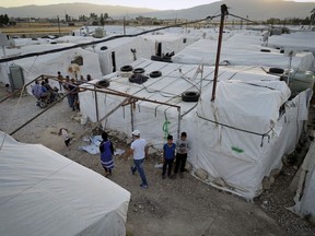 Syrian refugees walk by their tents at a refugee camp in the town of Bar Elias, in the Bekaa Valley, Lebanon, July 7, 2022. A funding shortfall for fragile Middle Eastern states who host refugees could lead to turbulence in international relations, warns the UN refugee chief for that region.