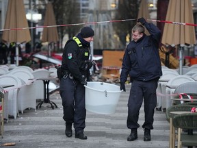 Police officers carry a plastic tub with rescued fish after a huge aquarium bursts in Berlin, Germany, Friday, Dec. 16, 2022. German police say a huge fish tank in the center of Berlin has burst, causing a wave of devastation in and around the Sea Life tourist attraction.