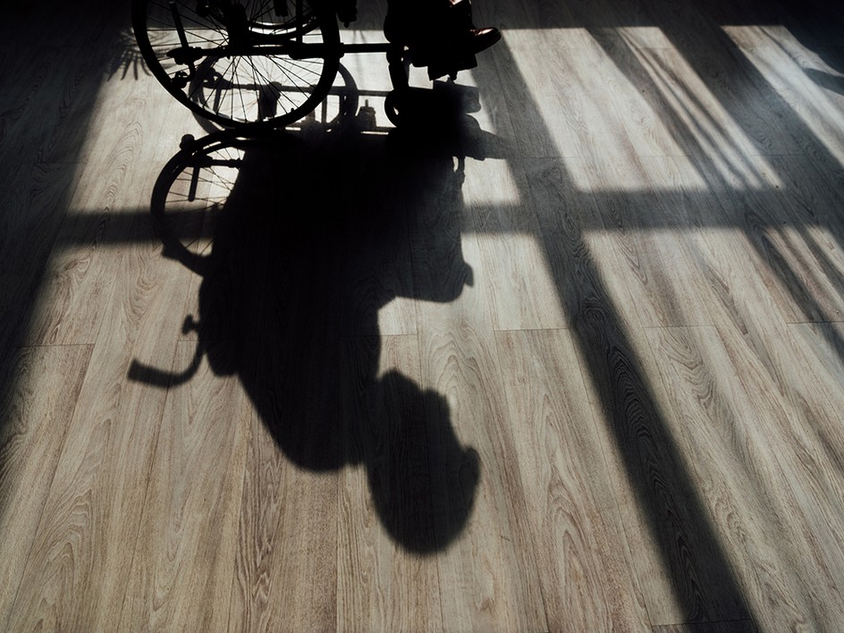 A photo of a shadow on a floor shows a person in a wheelchair.