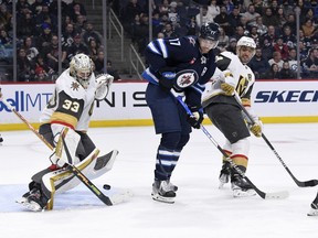 Vegas Golden Knights goaltender Adin Hill (33) makes a save as Winnipeg Jets' Adam Lowry (17) and Alec Martinez (23) look for the rebound during second period NHL action in Winnipeg on Tuesday December 13, 2022.