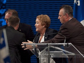 Parti Québécois Leader Pauline Marois is removed from the stage by provincial police officers as she speaks to supporters following her election win, in Montreal, Tuesday, Sept. 4, 2012. A Superior Court judge has found that police security on Quebec's 2012 election night was deficient and permitted a gunman to carry out an attack.