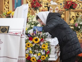 Galyna Legenkovska, mother of seven-year-old Mariia Legenkovska, leans over her daughter's casket during her funeral in Montreal, Wednesday, Dec. 21, 2022. Mariia Legenkovska, whose family moved to Montreal this year to flee the Russian invasion, was killed while walking to school with her brother and sister on Dec. 13 by a driver who didn't stop to assist her.