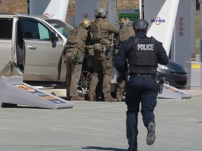 RCMP officers prepare to take a person into custody at a gas station in Enfield, N.S. on Sunday April 19, 2020. Transcripts of calls between the RCMP and search and rescue officials in Halifax show an overall lack of understanding of what was required to have a military aircraft assist during the search for a gunman who killed 22 people in April 2020.