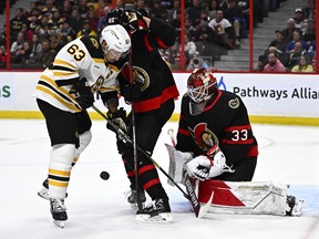 Boston Bruins left wing Brad Marchand (63) tries to get his stick on the puck as Ottawa Senators defenceman Nikita Zaitsev (22) defends in front of goaltender Cam Talbot (33) during first period NHL hockey action in Ottawa, on Tuesday, Dec. 27, 2022.