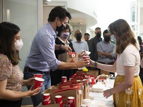 Prime Minister Justin Trudeau pours a cup of hot chocolate as he visits residents affected by Saturday's major storm at a community centre set up to provide food, showers, wifi and device charging to those who remain without power, in Ottawa, Thursday, May 26, 2022.