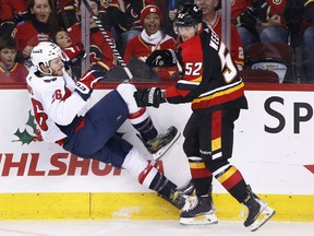 Washington Capitals' Nic Dowd, left, is knocked down by Calgary Flames' MacKenzie Weegar during first period NHL hockey action in Calgary, Ab., Saturday, Dec. 3, 2022.