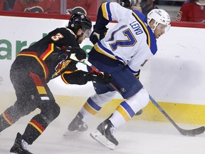 St. Louis Blues' Josh Leivo, right, is slowed down by the stick of Calgary Flames' Connor Mackey during second period NHL hockey action in Calgary, Friday, Dec. 16, 2022.