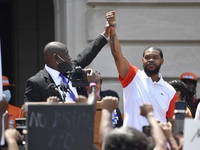 FILE - Attorney Benjamin Crump, left, holds up the hand of Kenneth Walker during a rally on the steps of the Kentucky State Capitol in Frankfort, Ky., on June 25, 2020. Walker, the boyfriend of Breonna Taylor who fired a shot at police as they burst through Taylor's door the night she was killed, has settled two lawsuits against the city of Louisville, his attorneys said Monday, Dec. 12, 2022.