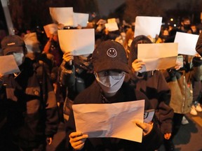 FILE - Protesters hold up blank papers and chant slogans as they march in protest in Beijing, Sunday, Nov. 27, 2022. In a society where everything is closely monitored and censored, the white paper is a silent protest against users not being allowed to speak.