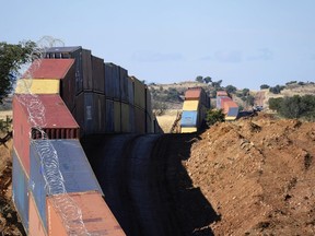FILE - A long row of double-stacked shipping containers provide a new wall between the United States and Mexico in the remote section area of San Rafael Valley, Ariz., Thursday, Dec. 8, 2022. Arizona Gov. Doug Ducey will take down a makeshift wall made of shipping containers at the Mexico border, settling a lawsuit and political tussle with the U.S. government over trespassing on federal lands.