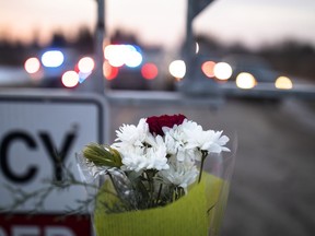 Flowers are left along Indian Line near Hagersville, Ont., Wednesday, Dec. 28, 2022, where an OPP officer was shot and killed. The body of an Ontario Provincial Police officer who was shot dead earlier this week will be brought to his hometown north of Toronto today.