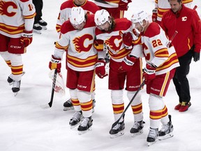 Calgary Flames' Chris Tanev is helped off the ice by teammates Rasmus Andersson, left, and Trevor Lewis after taking a puck to the head during second period NHL hockey action against the Montreal Canadiens in Montreal, Monday, Dec. 12, 2022.