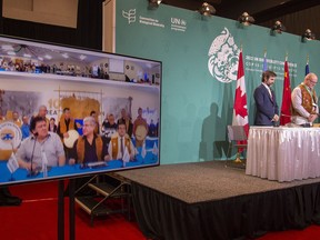 Minister of Environment and Climate Change Steven Guilbeault, left, and Northwest Territories MLA for Nahendeh Shane Thompson bow during a prayer performed via videoconference and shown on screen during a news conference at the COP 15 summit on biodiversity, in Montreal, Saturday, Dec. 17, 2022.