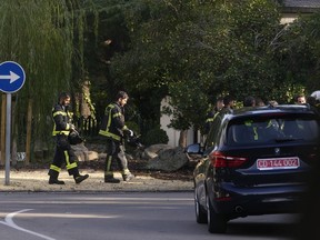 Firefighters walk past a diplomatic car by the Ukrainian embassy in Madrid, Spain, Wednesday, Nov. 30, 2022. Spain's Interior Ministry said police evacuated the Ukrainian embassy in Madrid on Friday after another suspect postal package was detected.