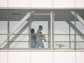 Health-care workers walk across a sky bridge at a hospital in Montreal, Sunday, Feb. 6, 2022. Researchers who study responsible artificial intelligence say a Montreal hospital network's plan to use AI to reduce emergency room wait times is an appropriate use of the technology, if it's done carefully.