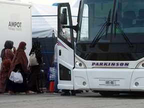 Refugees from Afghanistan board a bus after being processed at Pearson Airport in Toronto, Tuesday, Aug 17, 2021, after arriving indirectly from Afghanistan.