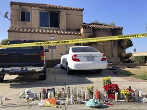 Dozens of candles are laid on the sidewalk, along with bouquets of flowers and stuffed animals outside of a charred home in Riverside, Calif., Wednesday, Nov. 30, 2022. Authorities believe a suspect parked his vehicle in a neighbor's driveway, walked to the home and killed the family members before leaving with a a teenage girl on Friday. Officials have not yet determined how the victims were killed or how the fire was set. The teenager was unharmed.
