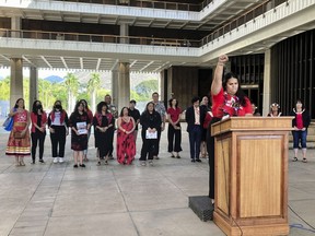 Makanalani Gomes, of AF3IRM, a feminist and decolonization organization, holds a fist in the air as she discusses a report on missing and murdered Native Hawaiian women, Wednesday, Dec. 14, 2022 in Honolulu.