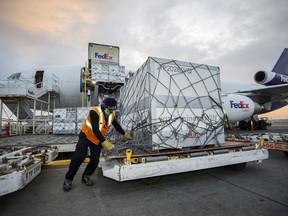 Workers unload a shipment of the Moderna COVID‑19 vaccine at the FedEx hub at Pearson International Airport in Toronto on May 20, 2021. Canada's auditor general is expected to release two highly anticipated reports on the government's handling of the COVID-19 crisis in 2021, including access to vaccines and pandemic benefits.