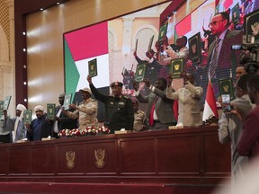Sudan's Army chief Gen. Abdel-Fattah Burhan, center, and others hold a document following the signature of an initial deal aimed at ending a deep crisis caused by last year's military coup, in Khartoum, Sudan, Monday, Dec. 5, 2022. Sudan's coup leaders and the main pro-democracy group signed a deal to establish a civilian-led transitional government following the military takeover last year. But key players refused to participate, and no deadline was set for the transition to begin.
