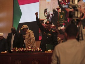 Sudan's Army chief Gen. Abdel-Fattah Burhan, center, holds up his fist as others hold a document following the signature of an initial deal aimed at ending a deep crisis caused by last year's military coup, in Khartoum, Sudan, Monday, Dec. 5, 2022. Sudan's coup leaders and the main pro-democracy group signed a deal to establish a civilian-led transitional government following the military takeover last year. But key players refused to participate, and no deadline was set for the transition to begin.