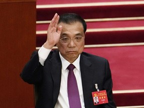 FILE - Chinese Premier Li Keqiang raises his hand to vote at the closing ceremony of the 20th National Congress of China's ruling Communist Party at the Great Hall of the People in Beijing on Oct. 22, 2022. Li praised the Hong Kong government's efforts in revitalizing the economy as it rolls back COVID-19 restrictions, in a meeting on Thursday, Dec. 22, 2022, with the territory's leader in Beijing.