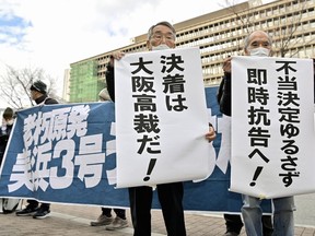 Petitioners display banners in front of Osaka District Court in Osaka, western Japan Tuesday, Dec. 20, 2022. A Japanese court ruled Tuesday that a 45-year-old nuclear reactor in central Japan is safe to operate, rejecting demands by local residents that it be suspended because of corrosion and inadequate safety measures _ a decision supportive of the government's push toward a greater use of nuclear energy amid power crunch concern and decarbonization obligation. The banners read "Unfair decision cannot be permitted. Immediate appeal!," right, and "We'll settle at Osaka Hight Court." (Kyodo News via AP)
