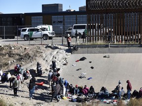 Migrants wait to cross the U.S.-Mexico border from Ciudad Juárez, Mexico, next to U.S. Border Patrol vehicles in El Paso, Texas, Wednesday, Dec. 14, 2022.