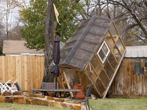 A greenhouse sits on a fence in the backyard of Randy Popiel's home after a possible tornado in Grapevine, Texas, Tuesday, Dec. 13, 2022.