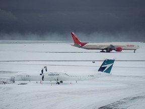Westjet and Air India aircraft sit idle at Vancouver International Airport after a snowstorm crippled operations leading to cancellations and major delays, in Richmond, B.C., on Tuesday, December 20, 2022.